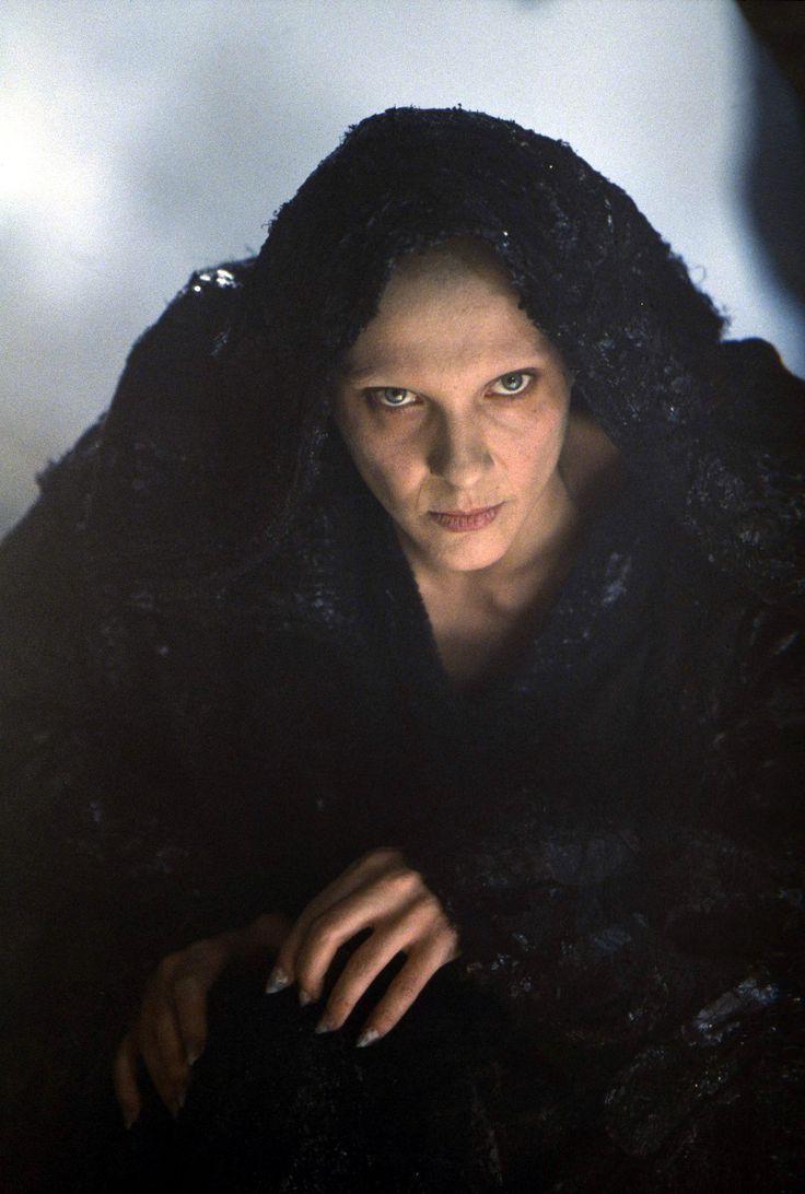 a woman wearing a black fur coat looking at the camera with an evil look on her face