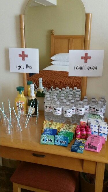 a wooden table topped with lots of bottles of water next to a dresser and mirror