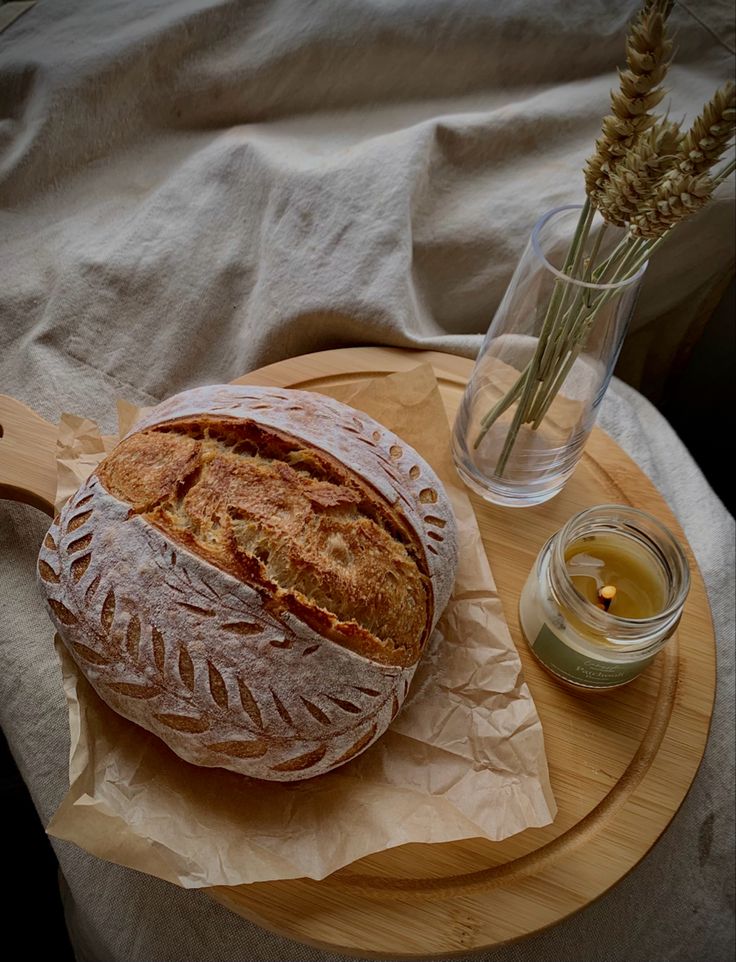 a loaf of bread sitting on top of a wooden cutting board next to a jar of honey