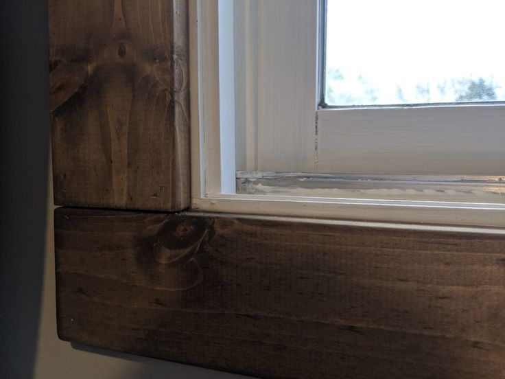 an open window on the side of a wooden building with white paint and wood trim