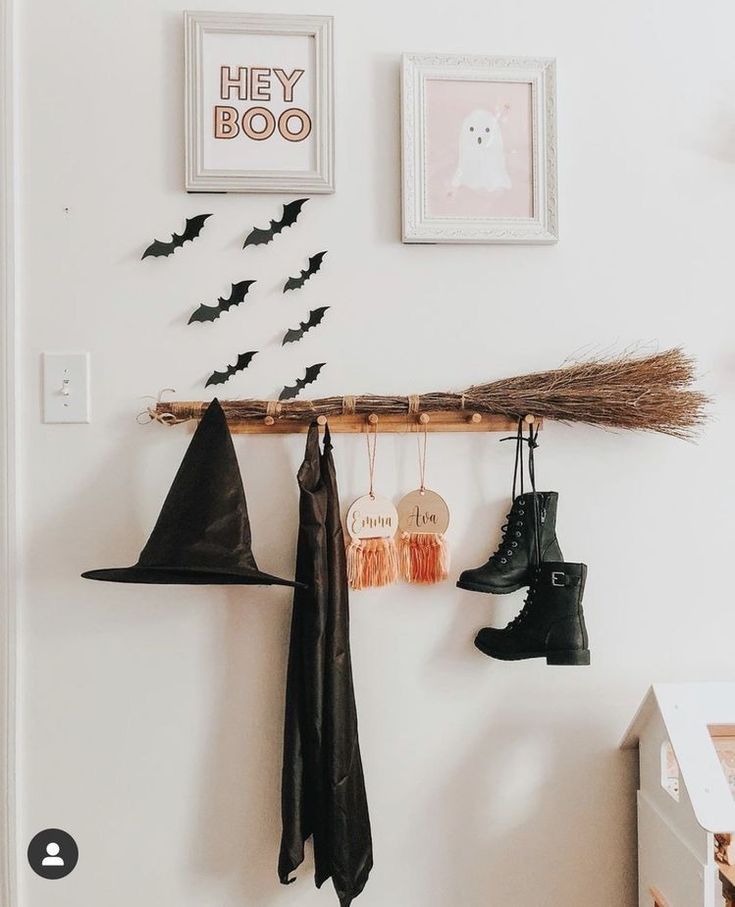 halloween decorations hanging on the wall with bats and brooms attached to hooks in front of them