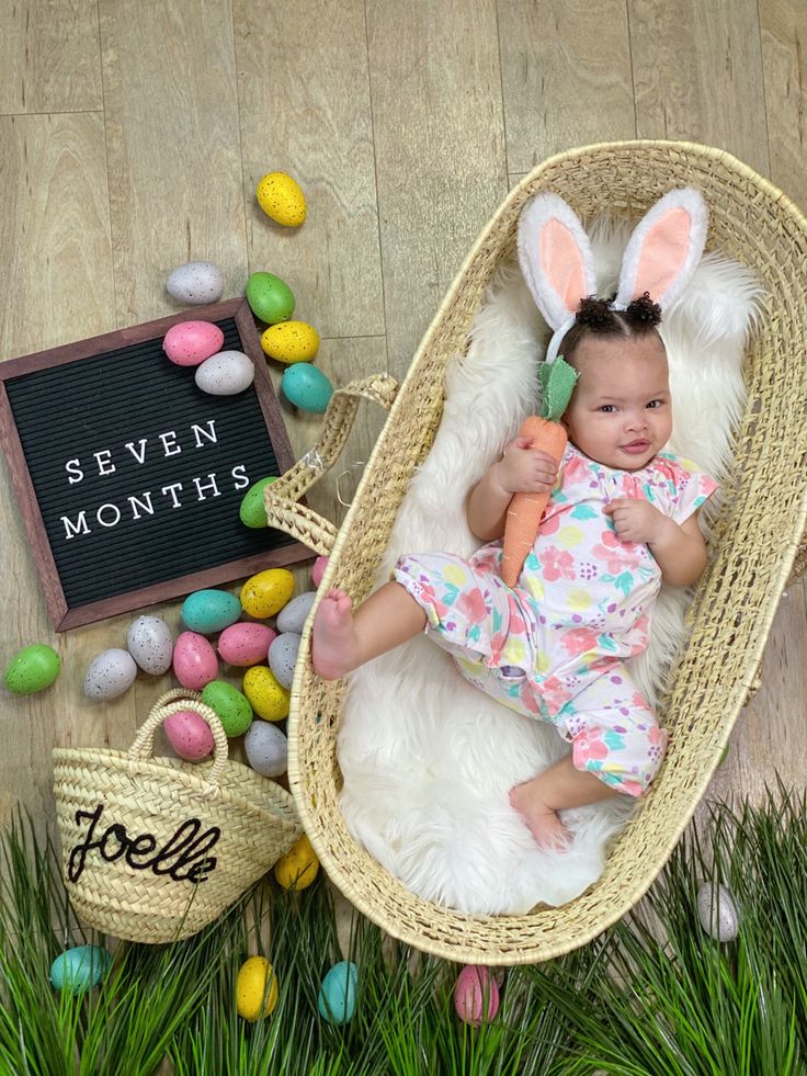 a baby is laying in a basket with easter eggs