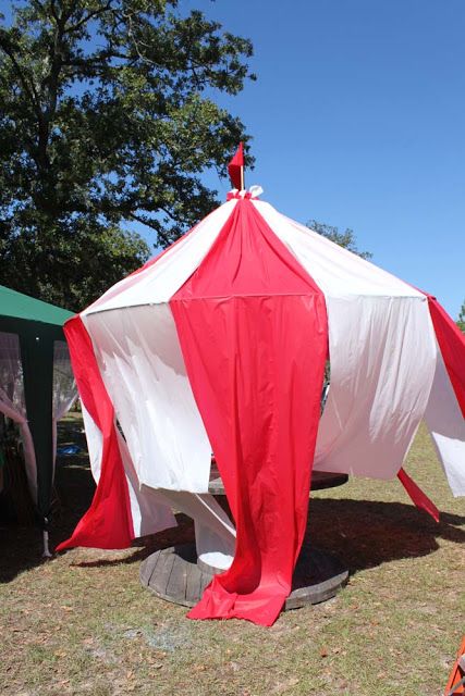 a red and white tent sitting on top of a grass covered field