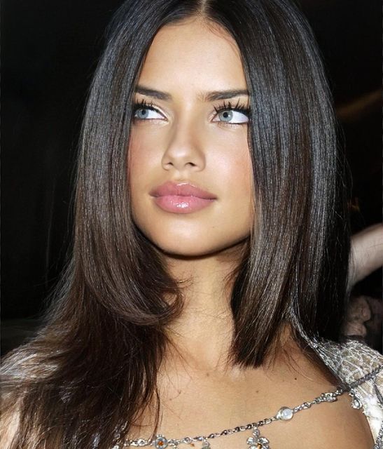 a close up of a woman with long hair and blue eyes wearing a necklace on her neck