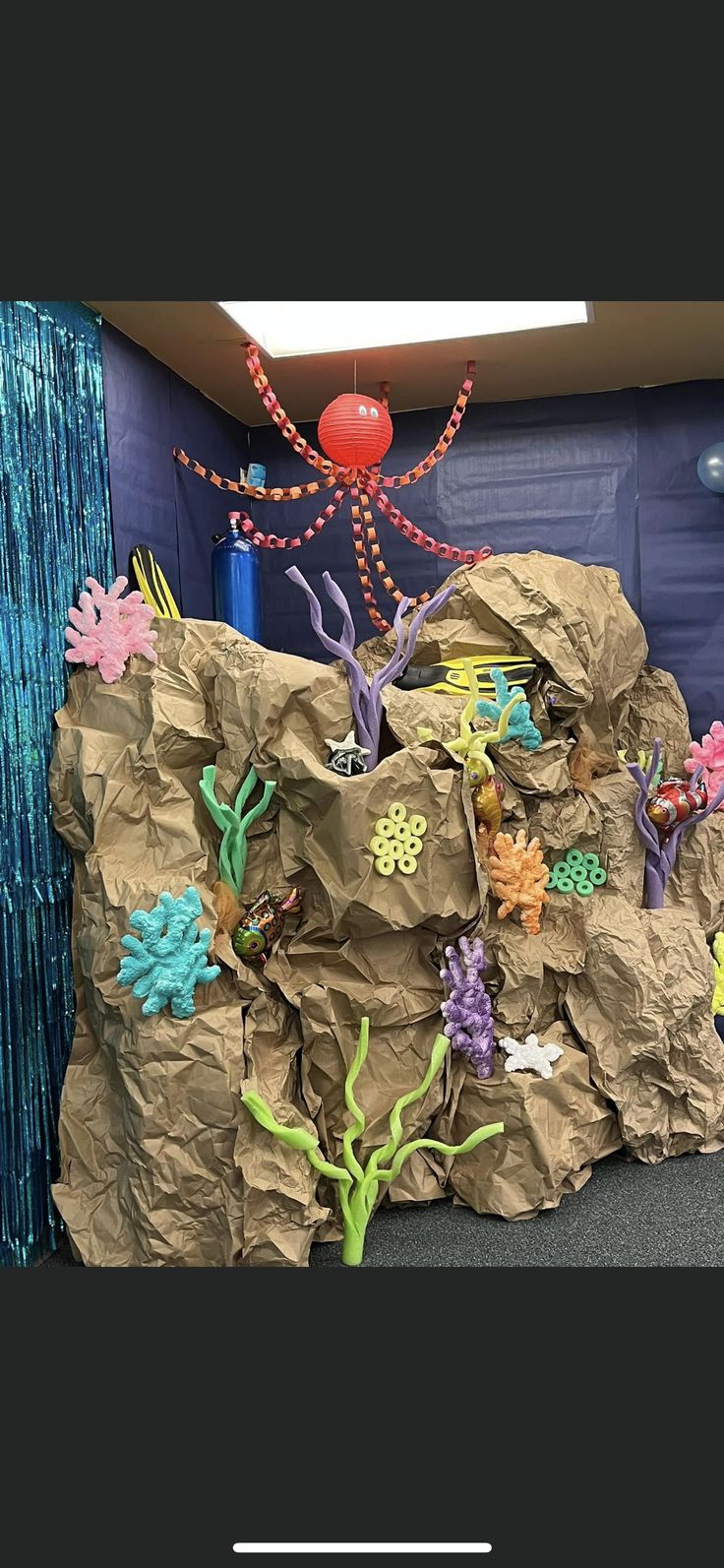 an under the sea themed birthday party with paper bags and decorations on display in front of a blue curtain