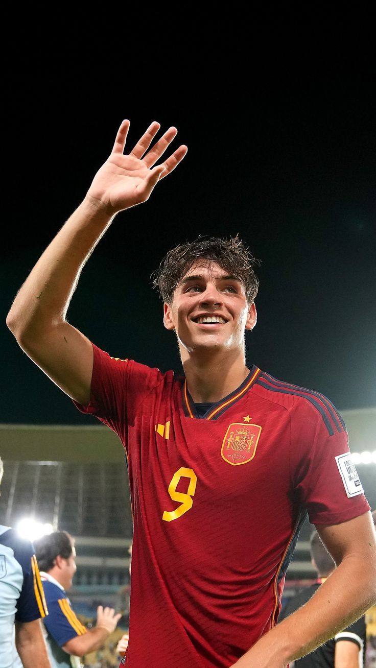 a soccer player is holding his hand up in the air and smiling at the camera