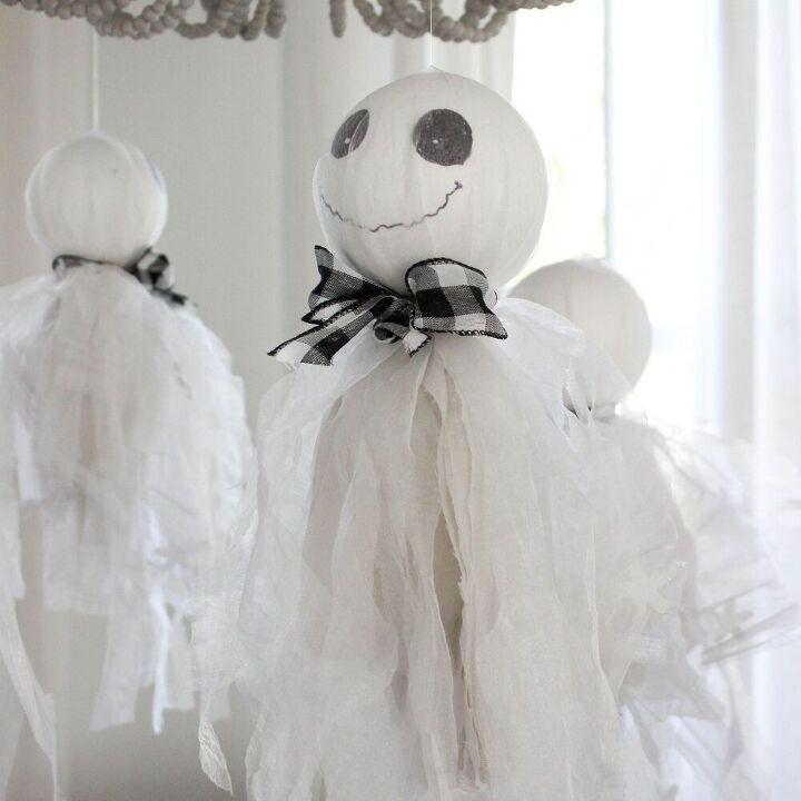 two white ghost decorations hanging from a chandelier