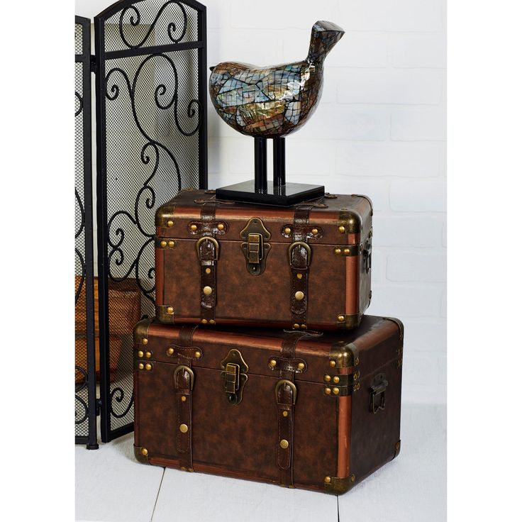 two suitcases stacked on top of each other with a bird statue sitting on top