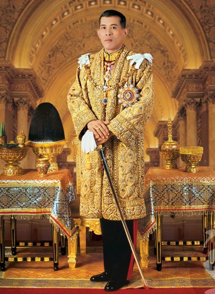 a man standing in front of a table wearing a gold coat and holding a cane