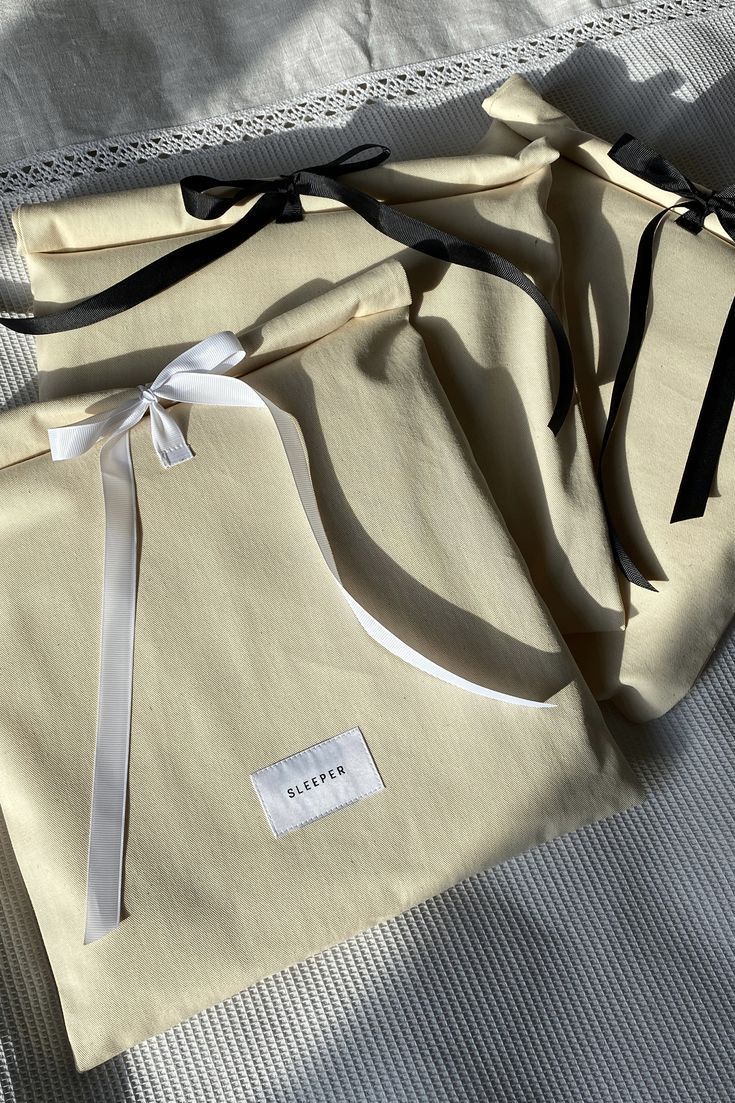 three pieces of cloth tied together on top of a bed with white sheets and black ribbons