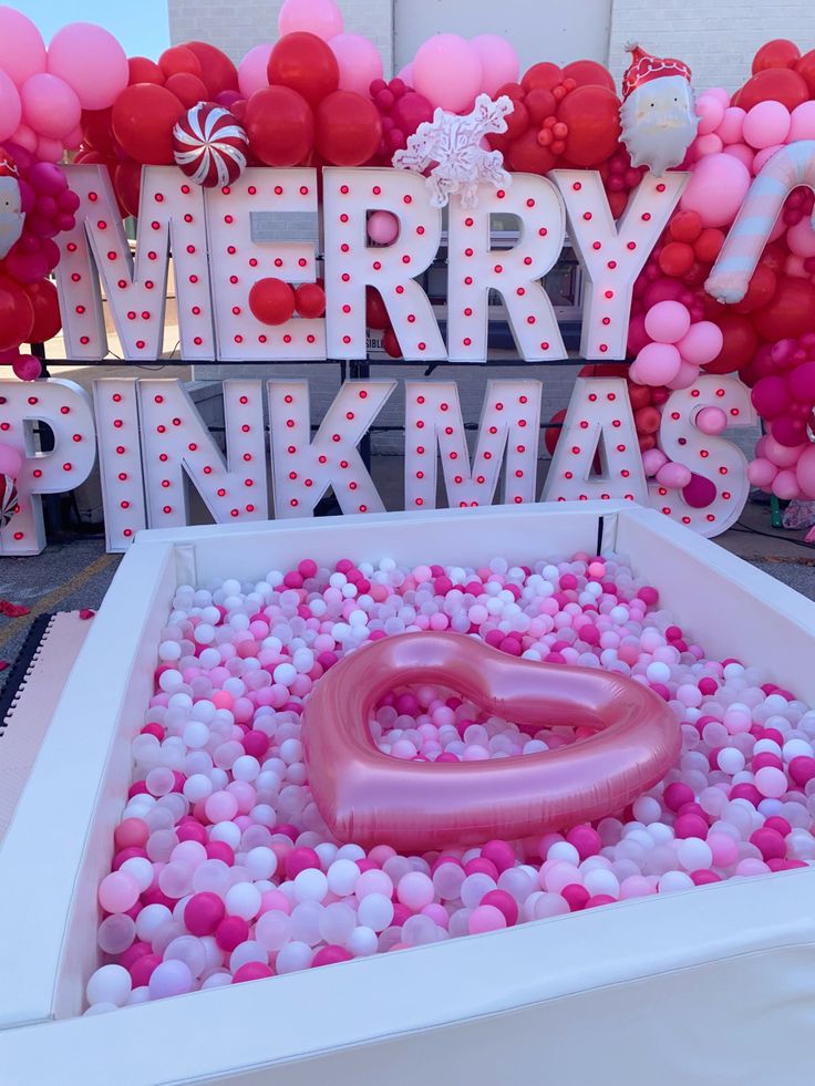 an inflatable heart surrounded by pink and white balloons with the words merry pinkma on it