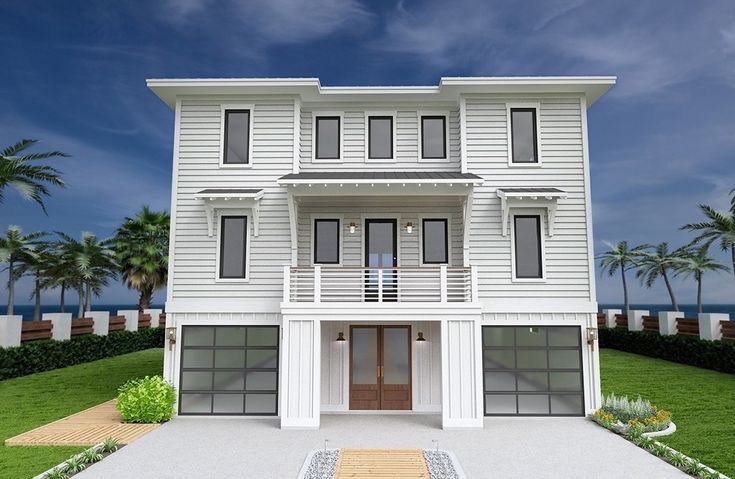 a large white two story house sitting on top of a lush green field next to the ocean