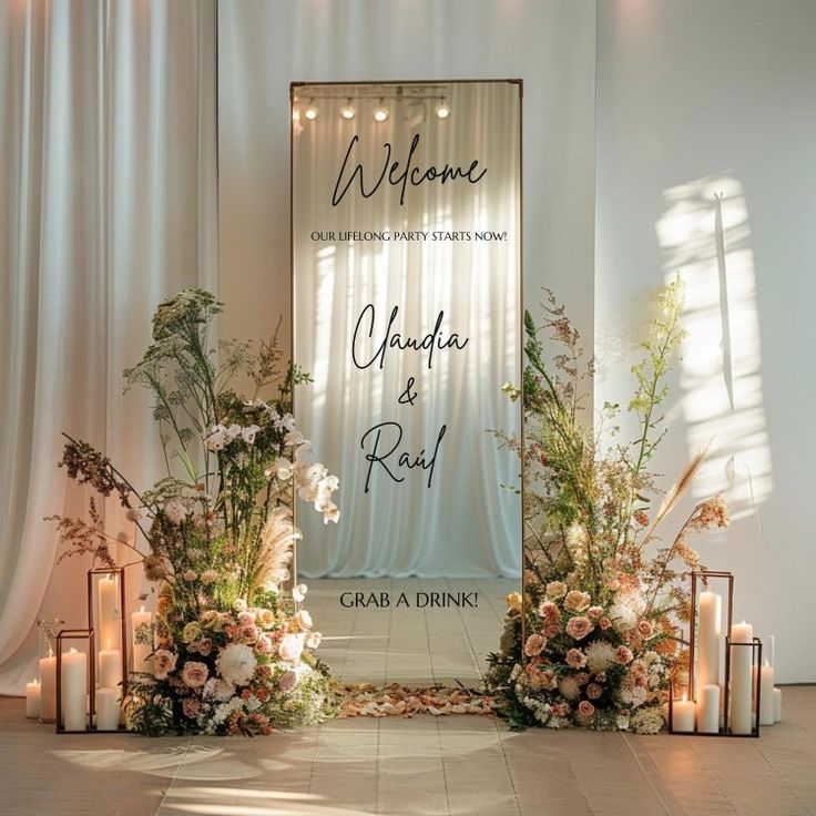 a wedding ceremony setup with candles and flowers on the floor in front of a welcome sign