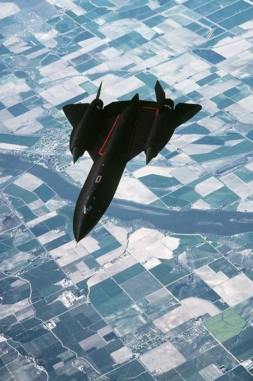 an airplane is flying in the sky over land and water, as seen from above