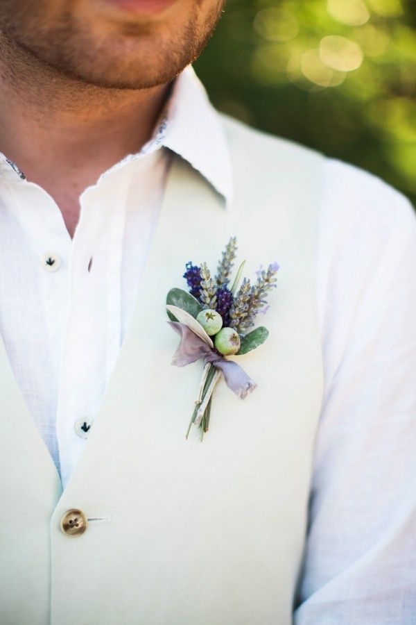 a man wearing a white vest and flower boutonniere