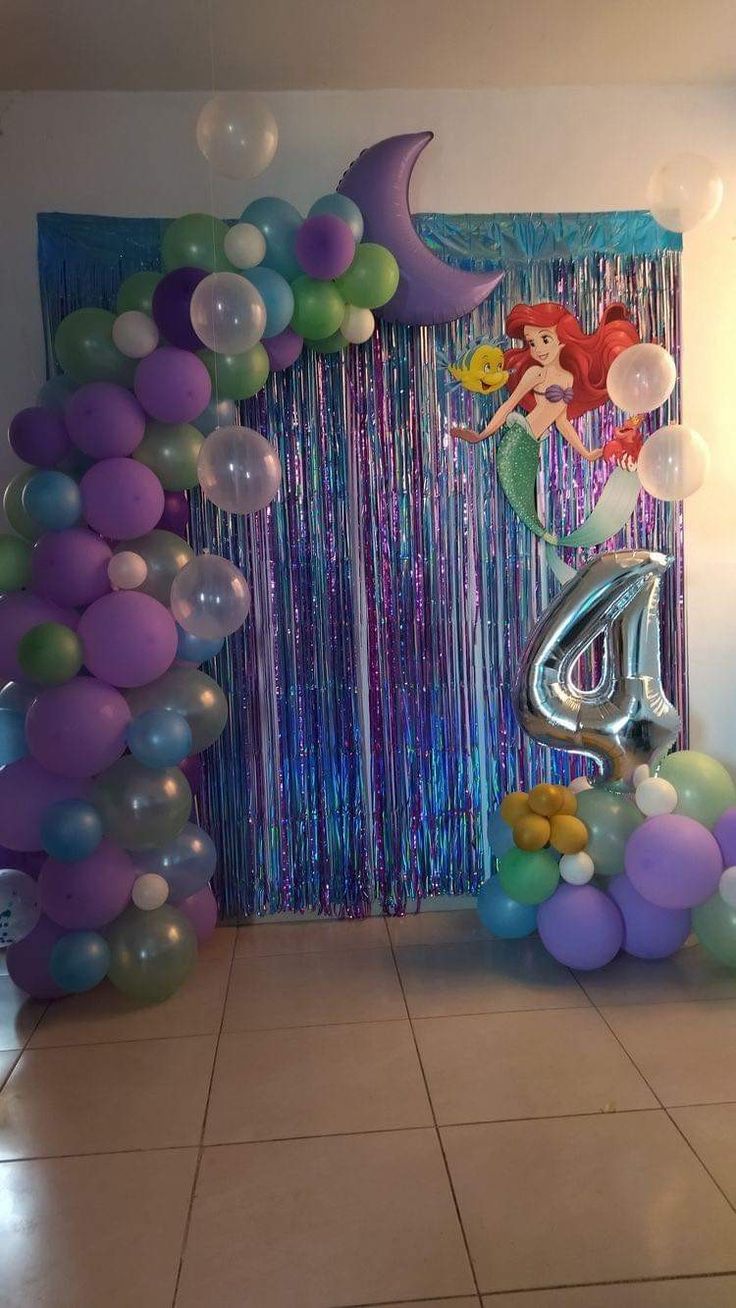 the balloon arch is decorated with mermaid balloons and streamers for an ariel birthday party