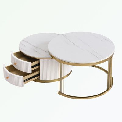 three white tables with gold accents on each side and one round table that has four drawers