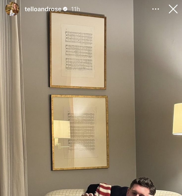 a man laying on top of a white couch next to a wall with two framed pictures