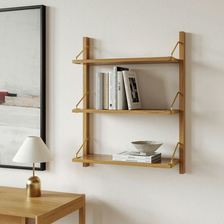 a wooden shelf with books on it next to a lamp and painting hanging on the wall