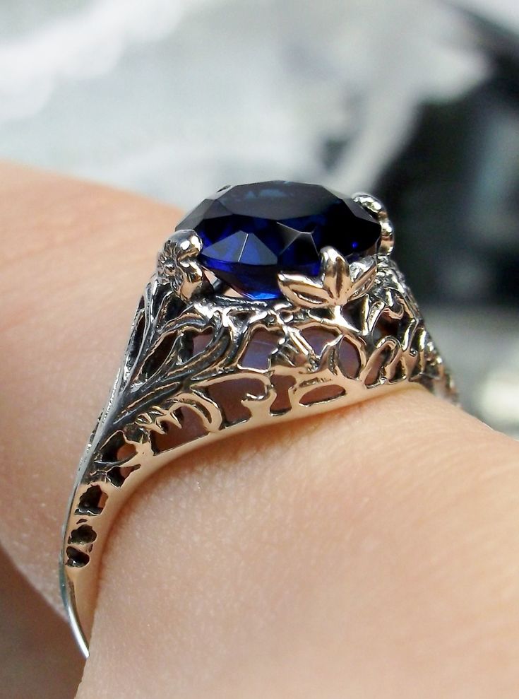 Simulated Blue Sapphire Ring  Coffee Design#198 This is a stunning Art Nouveau reproduction in sterling silver filigree with a 2ct Simulated Blue Sapphire stone. The flawless Simulated Blue Sapphire is 8mm in diameter. The inside of the band is marked 925 for sterling. Notice the beautiful craftsmanship of the silver filigree setting and band. This is a ornate and detailed ring. This is a lovely rendition of an antique filigree ring; and it is ready to wear. A gift ring box is included for safek Leaf Filigree, Sapphire Antique Ring, Victorian Ring, Antique Filigree, Art Nouveau Floral, Gothic Vintage, Sapphire Solitaire, Victorian Rings, Detailed Ring