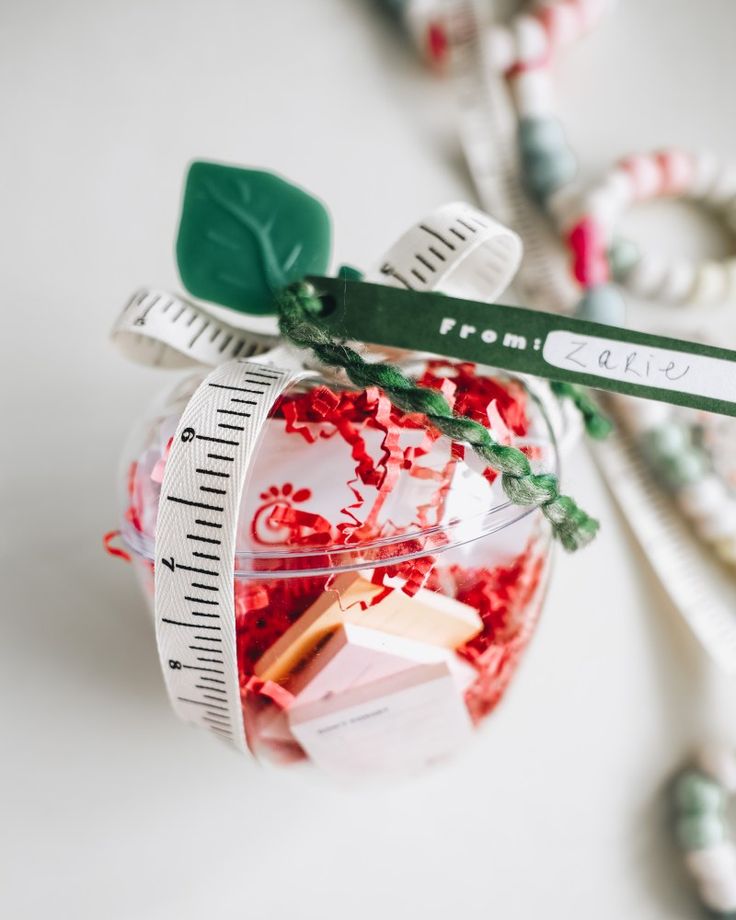 an ornament filled with candy and measuring tape on top of a white table