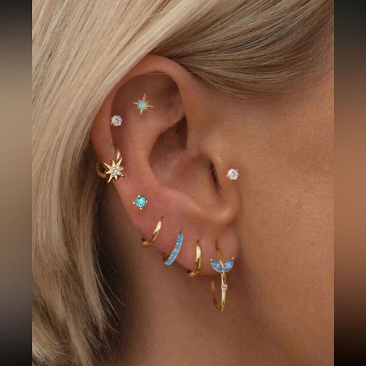 a woman's ear with star and moon piercings