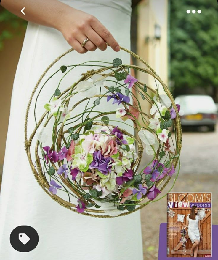 a woman holding a basket with purple and white flowers in it next to a book