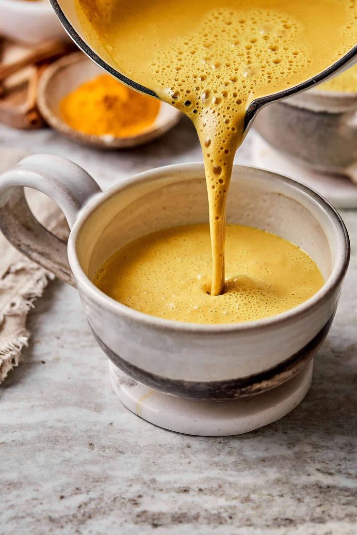 a pitcher pouring liquid into a cup filled with soup