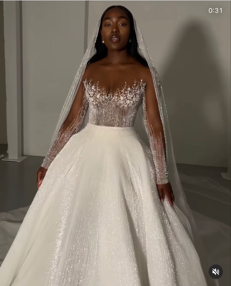 a woman in a white wedding dress with long sleeves and a veil on her head