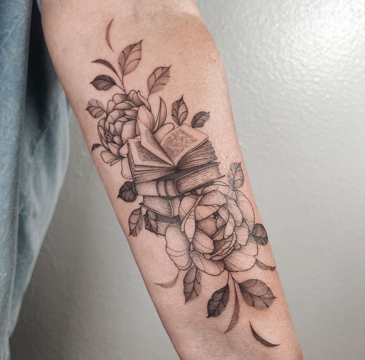 a woman's arm with a book and flowers on it