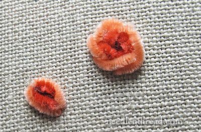 two small orange flowers sitting on top of a white cloth