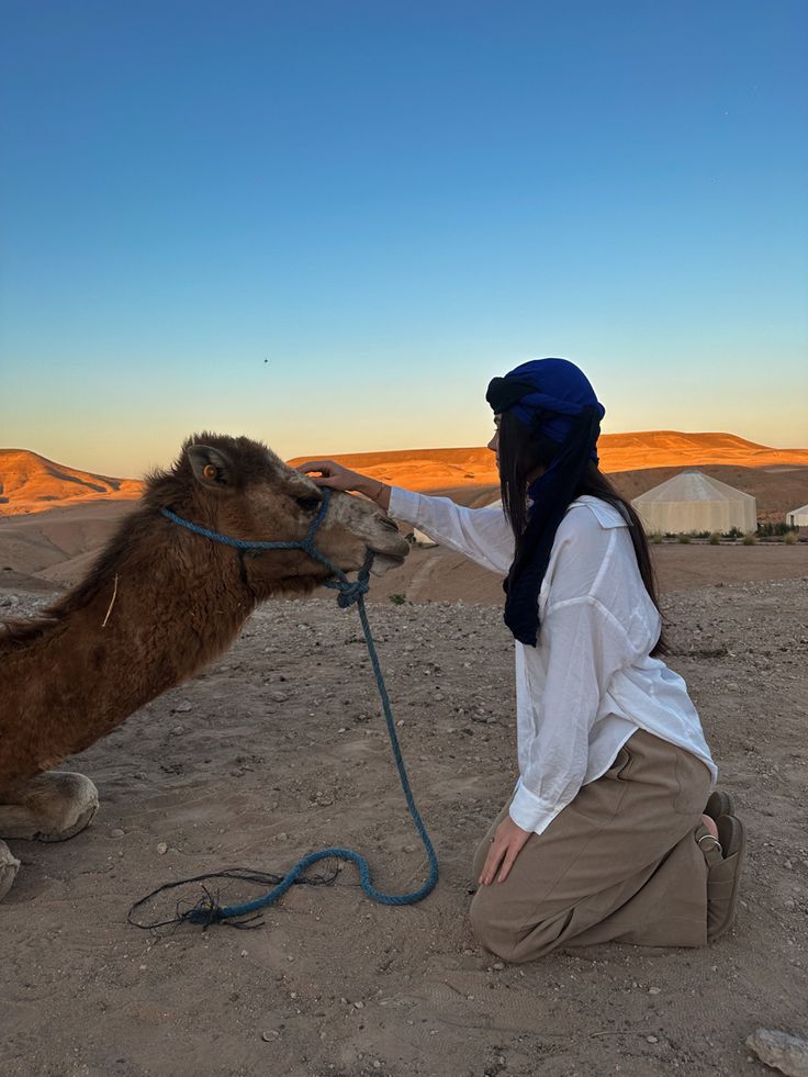 a woman is petting a camel in the desert