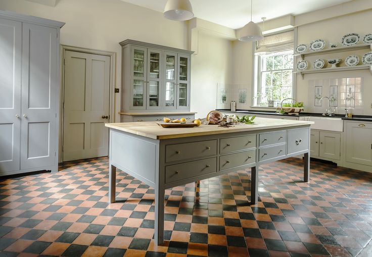 a kitchen with checkered flooring and white cupboards on the walls, an island in the middle