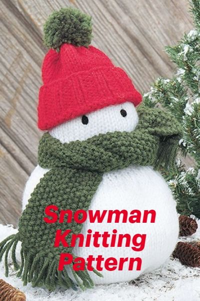 a knitted snowman wearing a red hat and scarf with pine cones around it