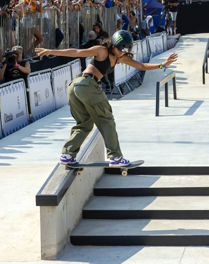 a woman riding a skateboard down the side of a rail