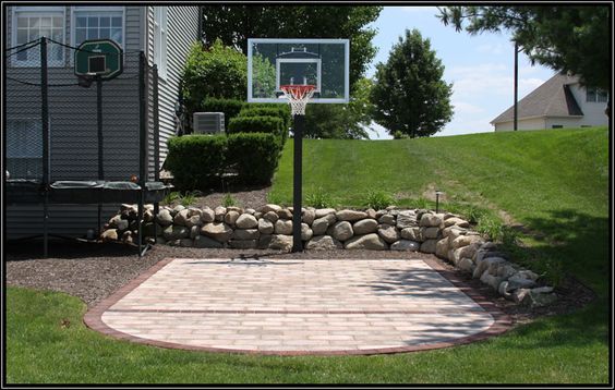 an outdoor basketball court surrounded by rocks and grass