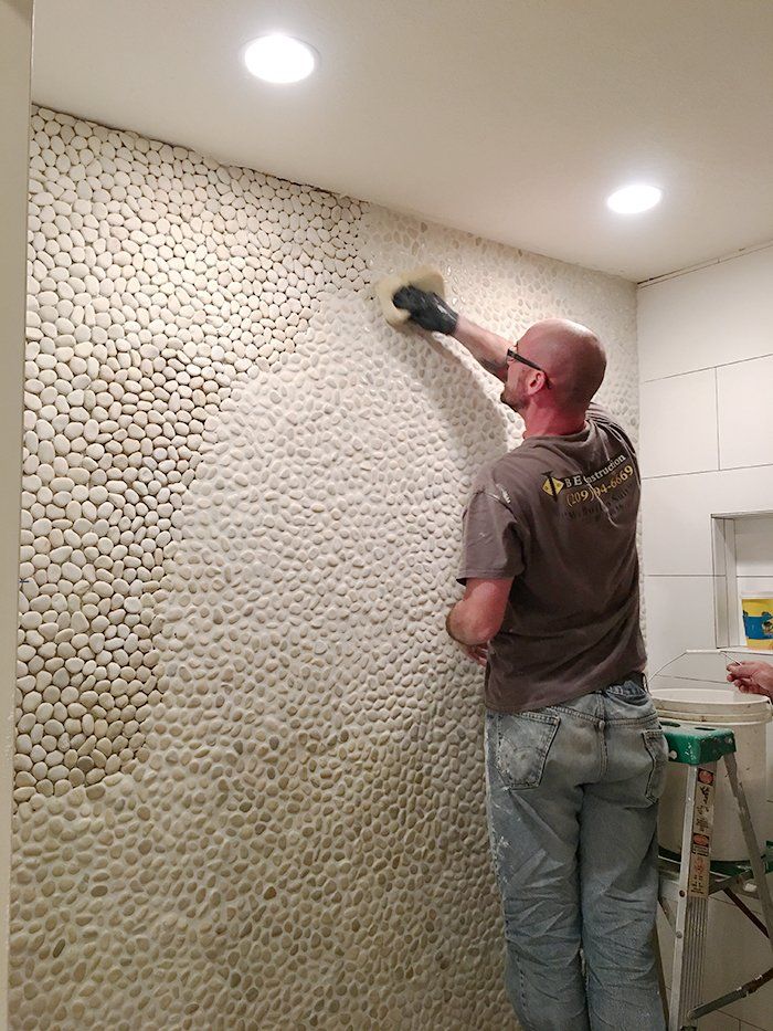 a man is painting a wall with white pebbles