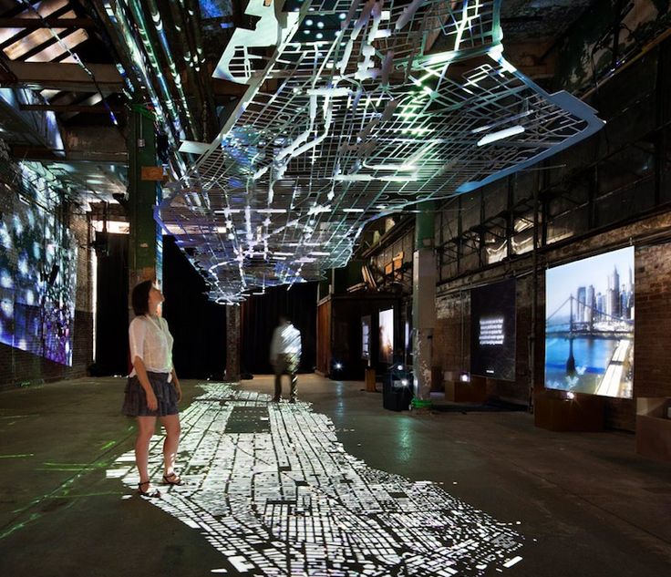 two people are standing in an open space with projected images on the walls and ceiling