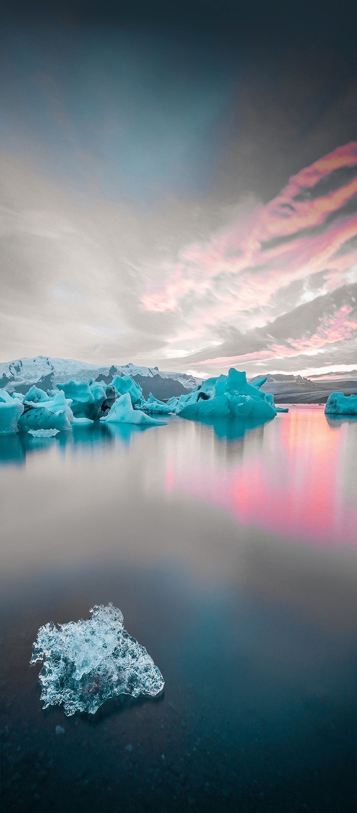 icebergs floating in the water at sunset with colorful clouds above and below them