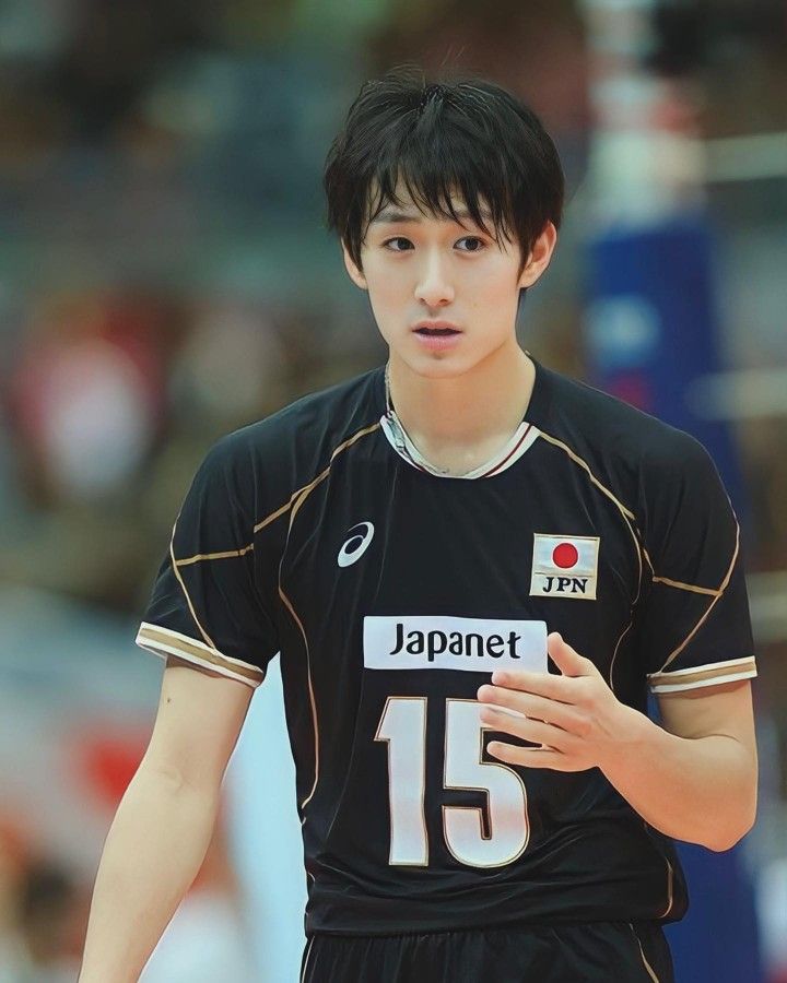 a young man wearing a black and white uniform holding a volleyball ball in his hand