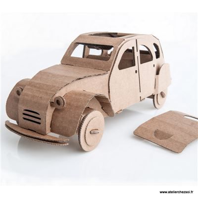 a car made out of cardboard sitting next to a piece of paper on a white surface