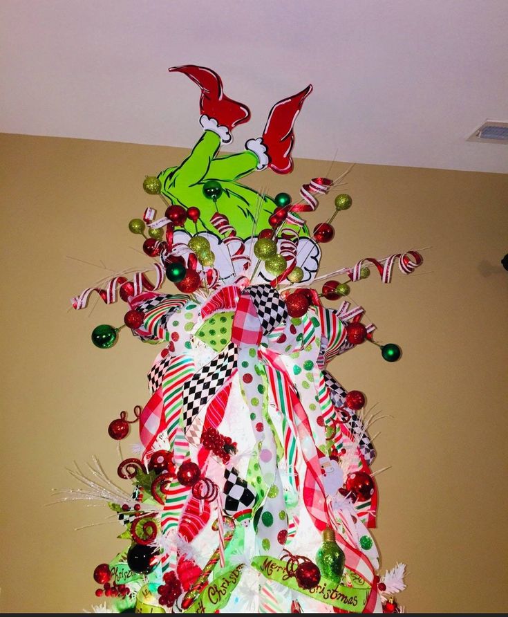 a christmas tree made out of candy canes and other holiday decorations is hanging on the wall