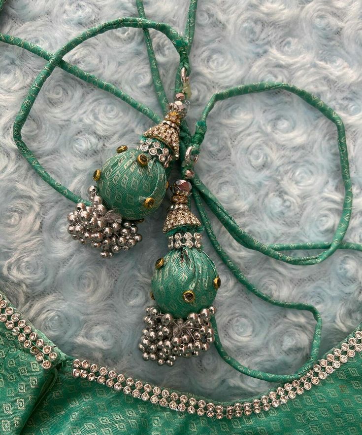 a green and silver necklace with beads on it sitting on a blue fabric covered surface