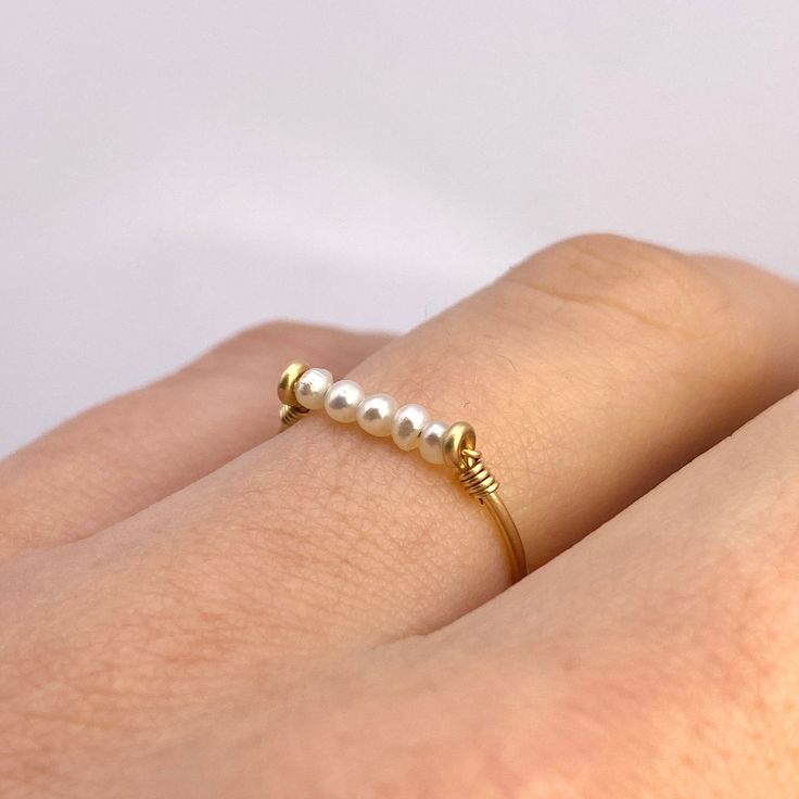 This beautifully simple ring is lovingly handmade with 5 tiny Freshwater Pearls and a choice of 14k Gold Filled, 14k Rose Gold Filled or Sterling Silver band. M A T E R I A L S: * Freshwater Pearl * 14k Gold Filled, 14k Rose Gold Filled or Sterling Silver S I Z E: *  Gemstone - Approximately 2mm each *  Band Thickness - Approximately 0.8-1mm  All of our jewellery is carefully handmade using good quality materials and handpicked gemstones, with the aim to produce quality pieces that you can love 14k Gold Filled Stackable Rings As Gift, Dainty Handmade Midi Rings For Anniversary, Simple Design Gold Stackable Rings As Gift, Dainty Pearl Ring With Simple Design For Gift, Dainty Pearl Ring With Simple Design, Dainty Handmade Stackable Rings For Anniversary, Dainty Pearl Ring With Simple Design As A Gift, Handmade Dainty 14k Gold Midi Rings, Minimalist Handmade Pearl Ring For Anniversary