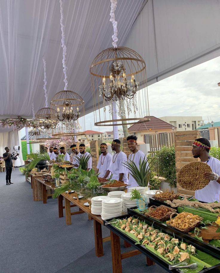 a group of men standing around a table filled with food