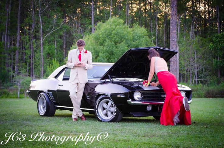 a man and woman standing next to a car