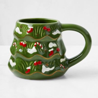 a green ceramic mug with red and white flowers on the inside is sitting on a table