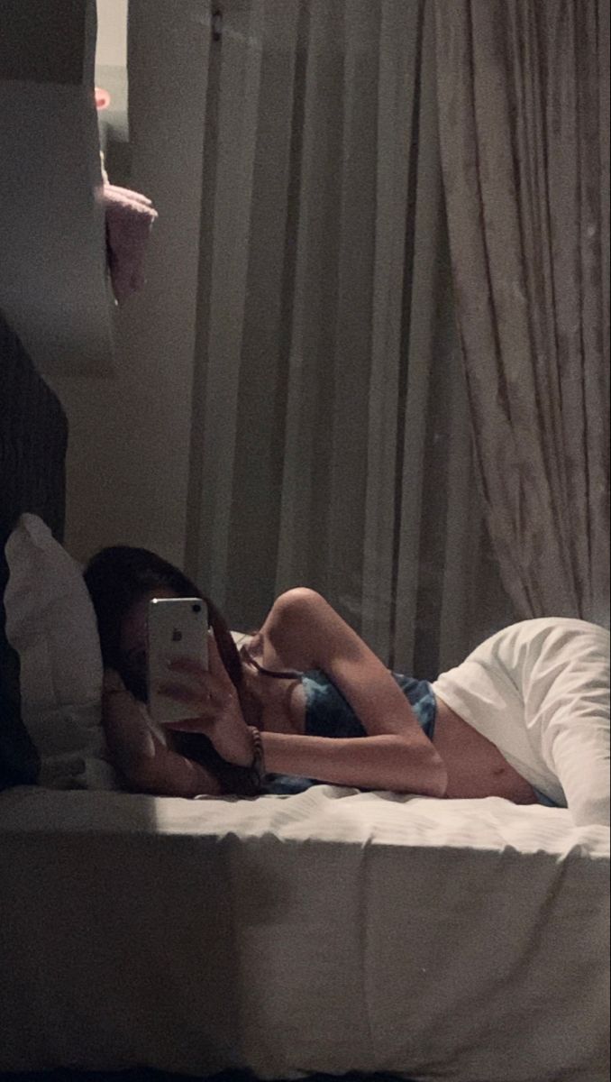 a woman laying in bed looking at her cell phone