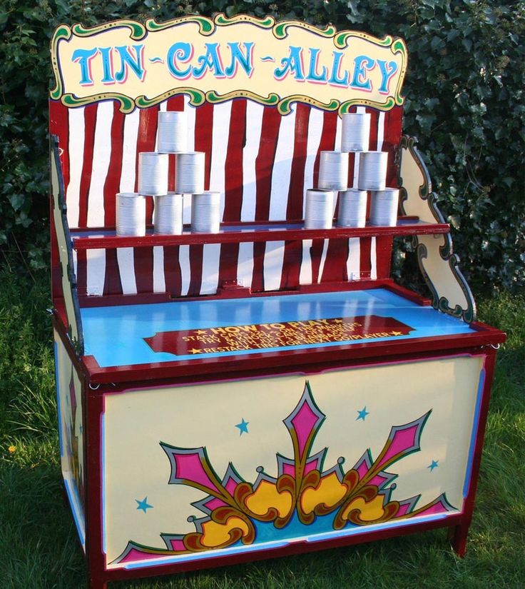 an old fashioned candy machine with tin can alley on it's side in the grass