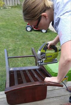 a woman is sanding the back of a bench with a power plane on it